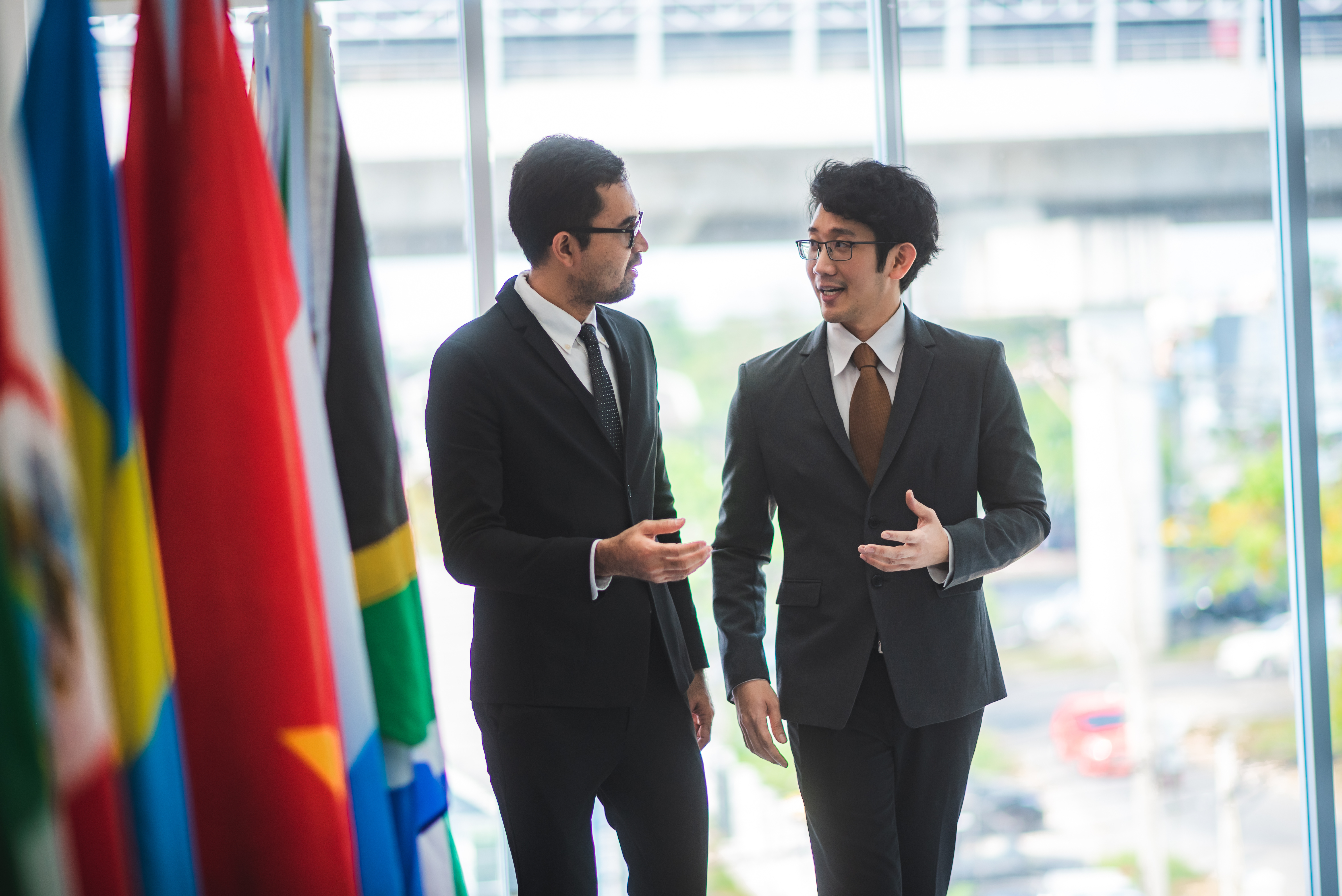 Men in suits discuss business near international flags