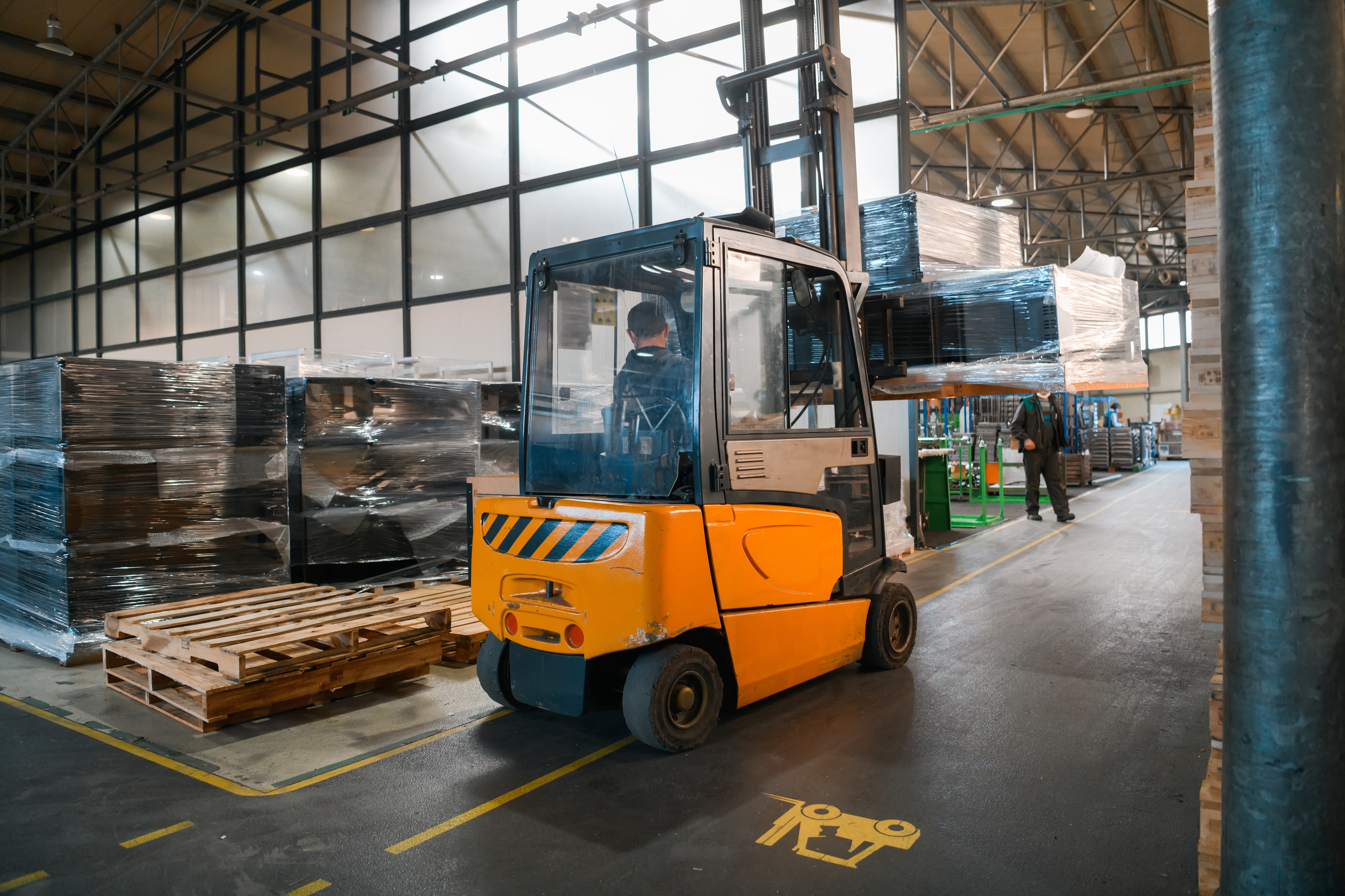 A forklift carrying a pallet of goods drives through a distribution warehouse