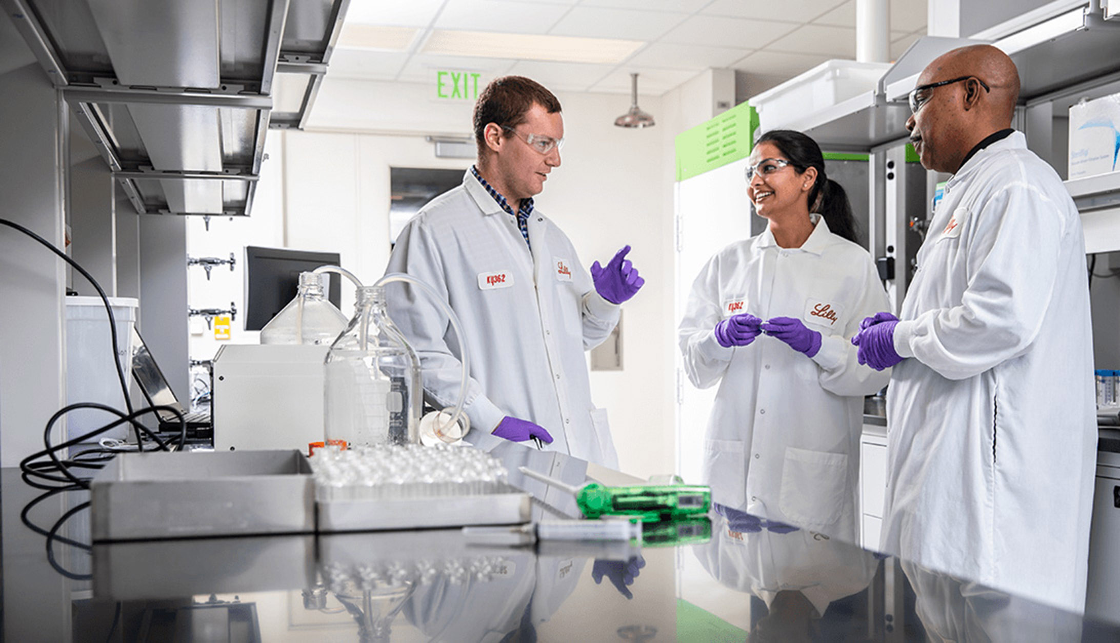 Three Eli Lilly employees talk as they work in a laboratory