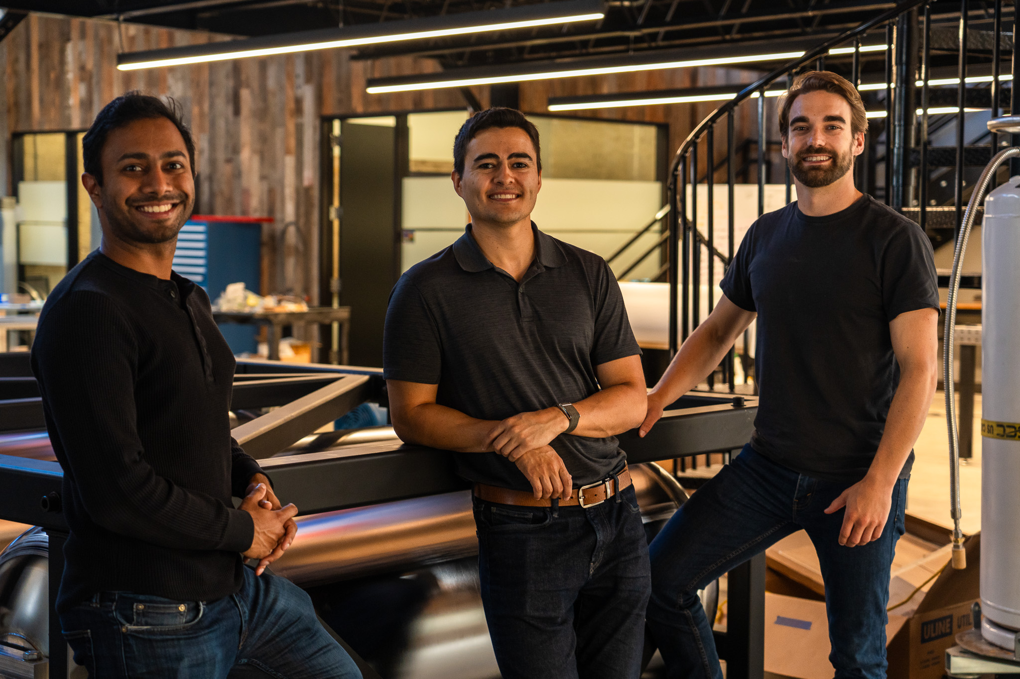 The founders of Verne pose for a photo in a sleek industrial office with warm lighting