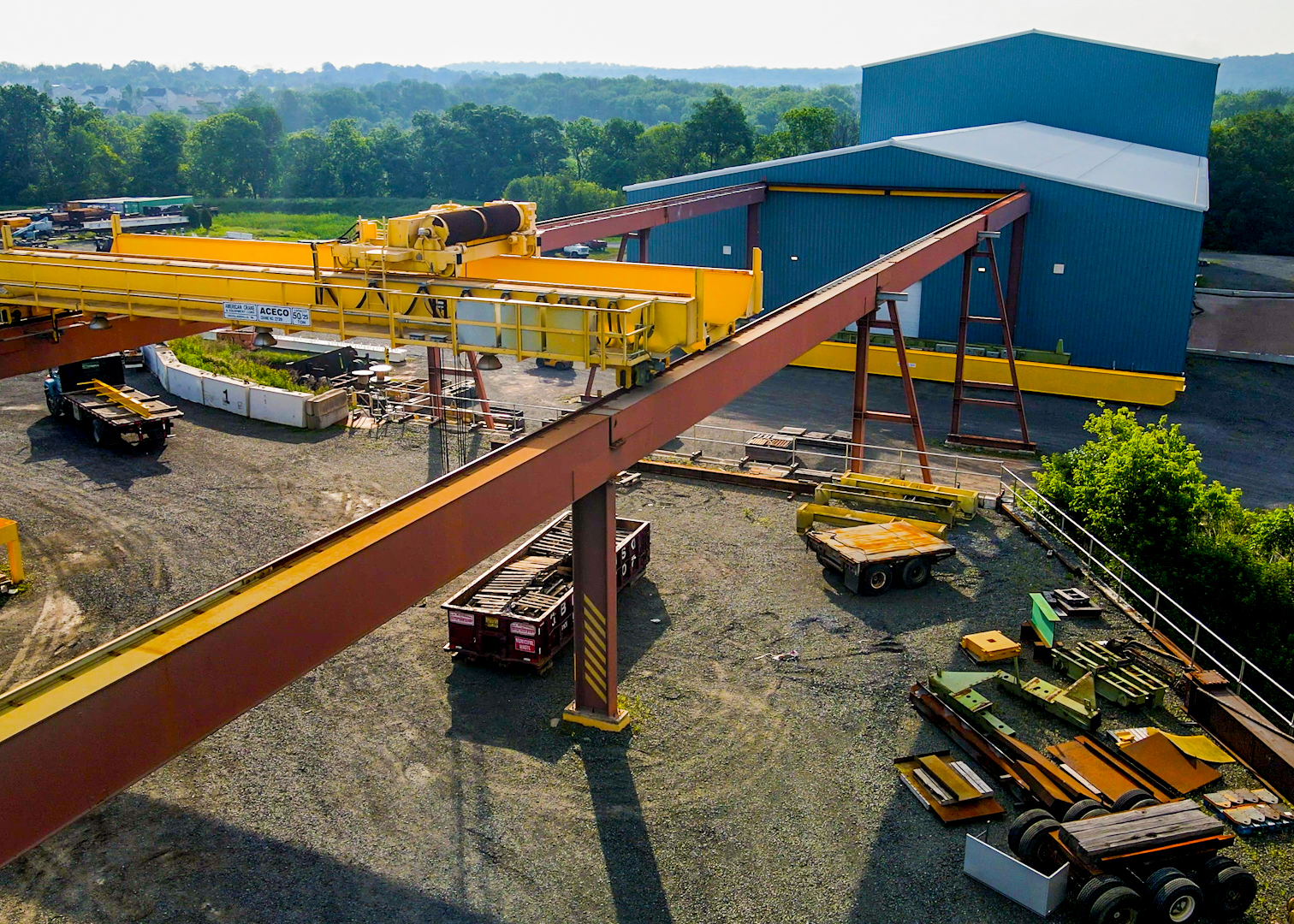 A large industrial crane in a dirt construction lot near an industrial building.