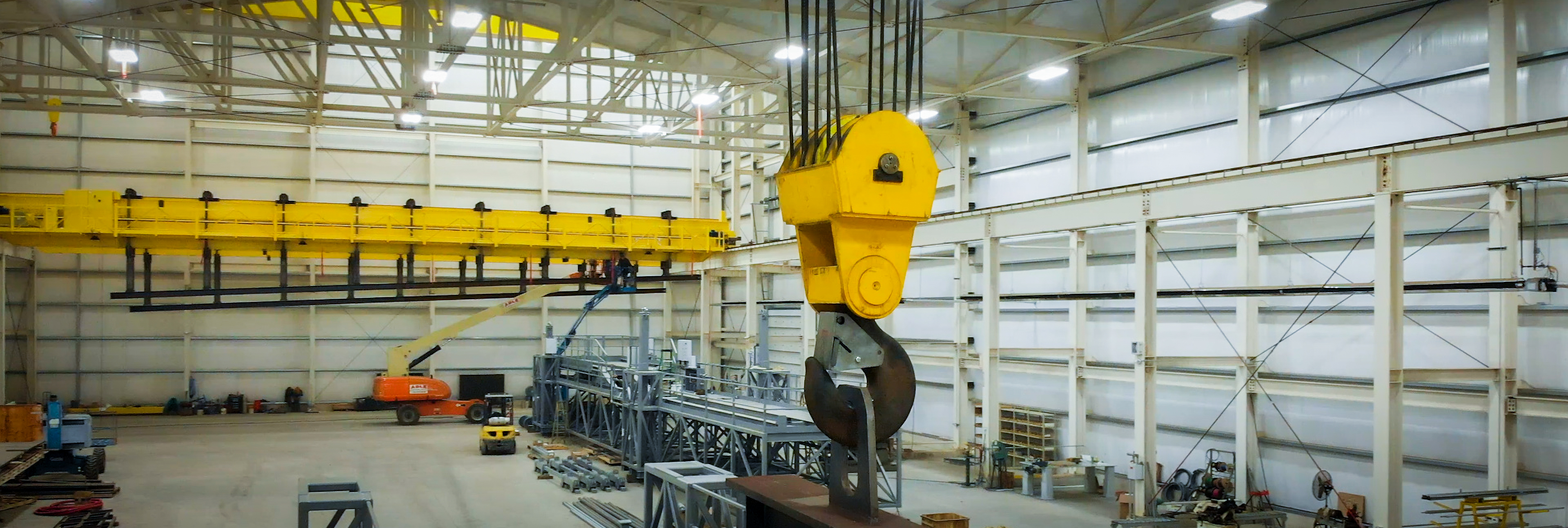 The hook of a lrge industrial crane, inside an industrial building.