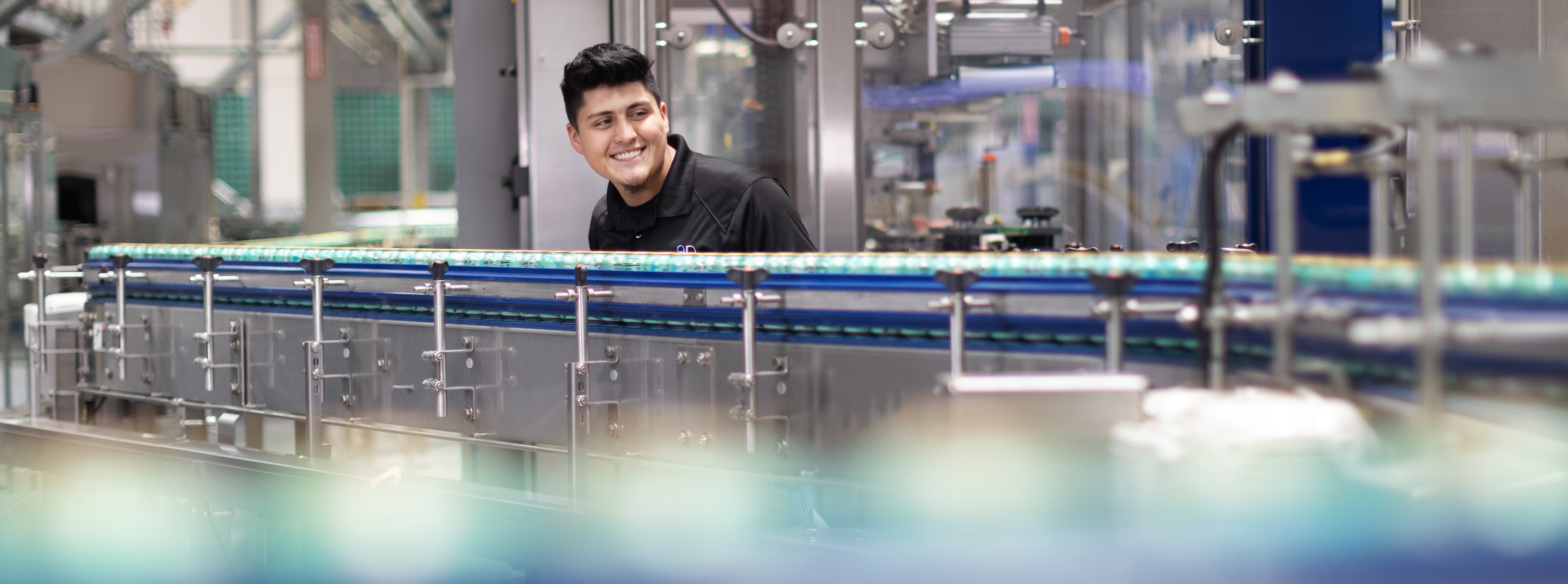 Worker observes automated beverage bottling line in factory