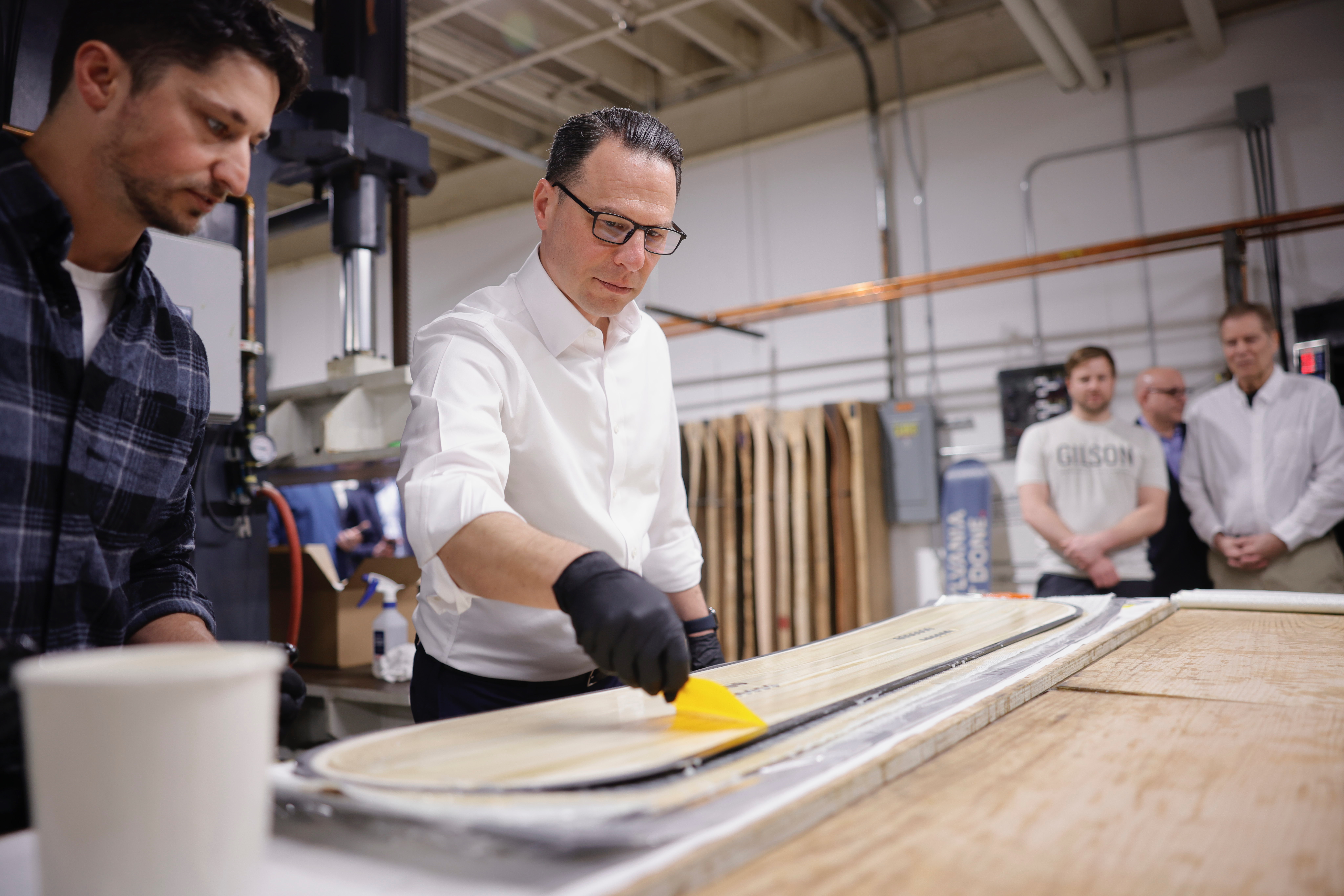 PA Governor Josh Shapiro spreads wax on a made in PA snowboard. 