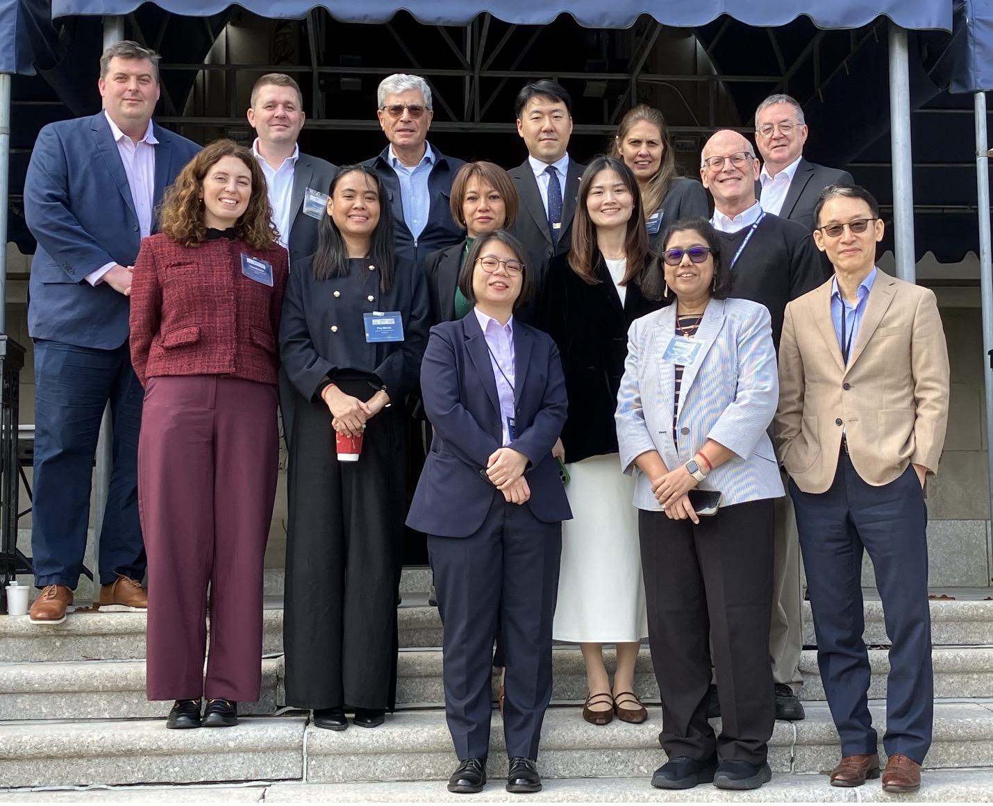 A group photo of international businesspeople smiling on the steps of a building