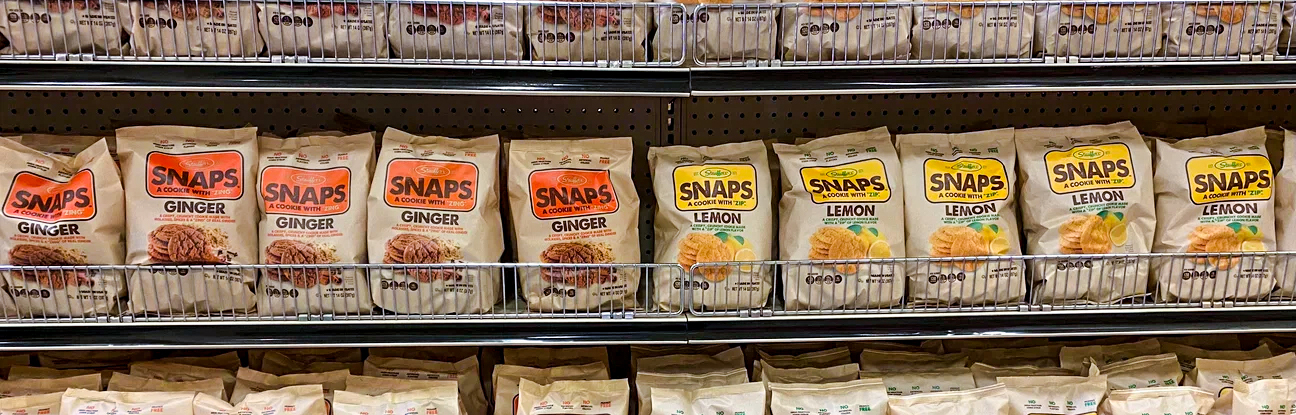 Many packages of the snack called Snaps fill shelves at a grocery store.