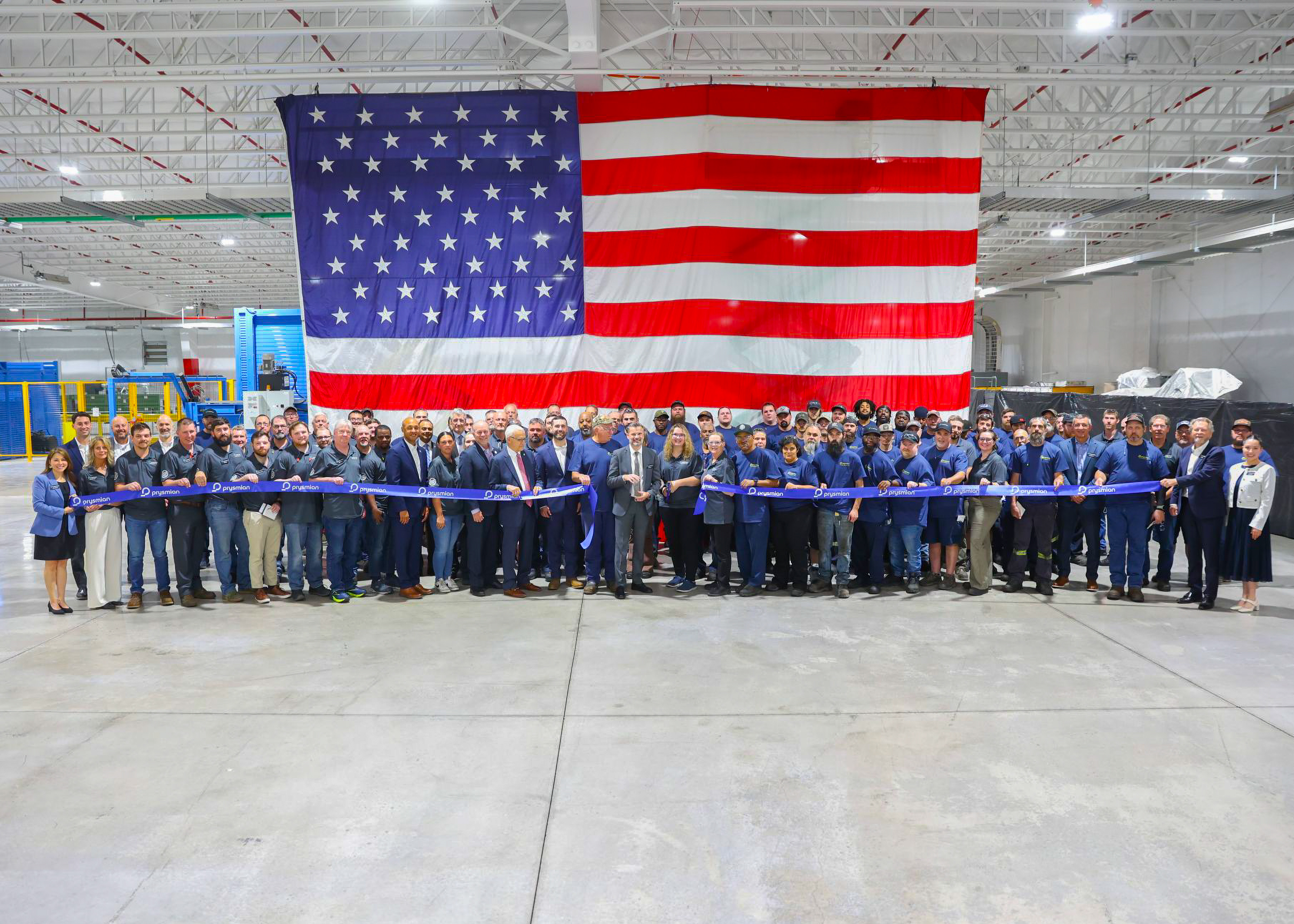 Large group ribbon cutting in front of American flag