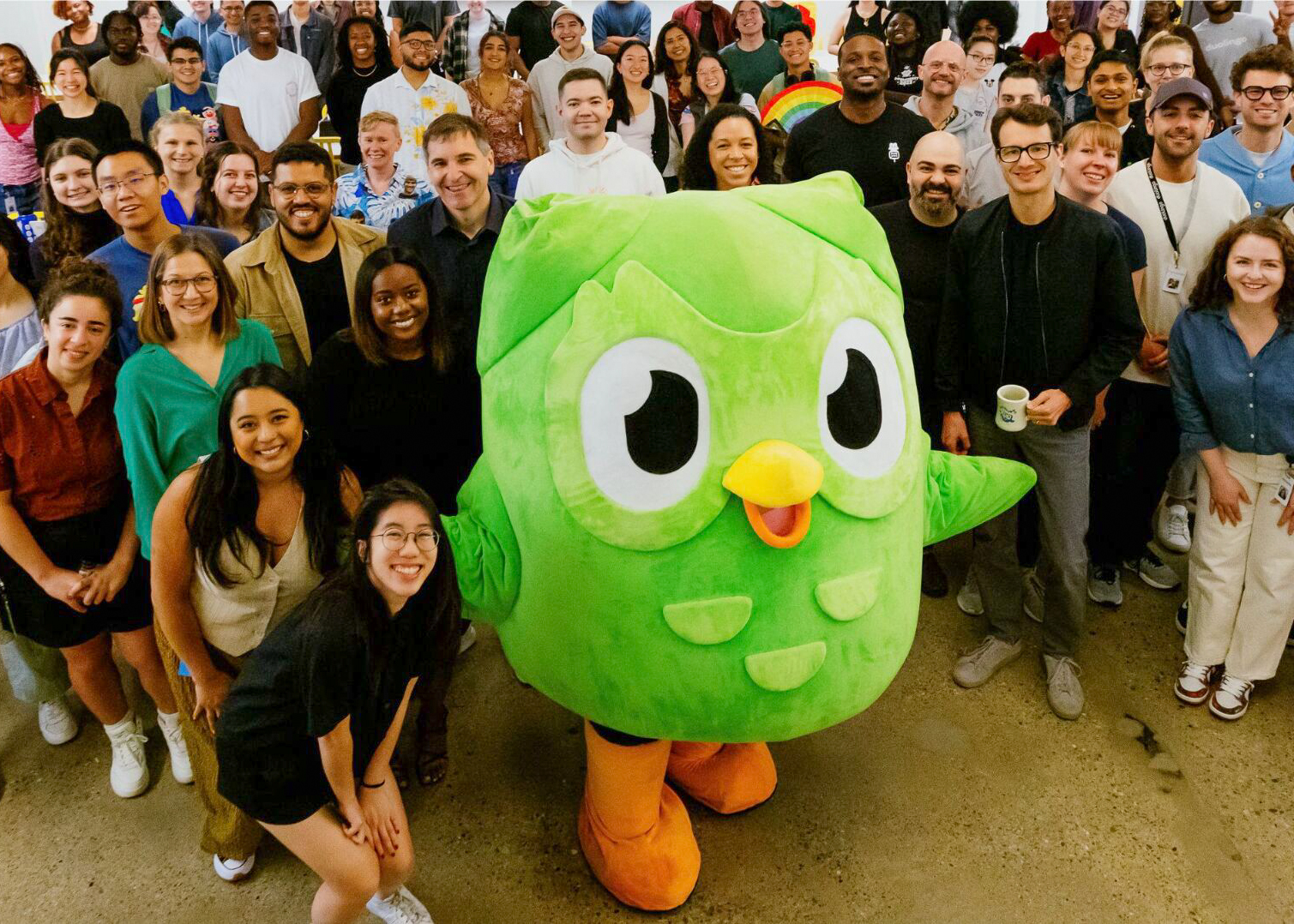 Large green owl mascot with crowd
