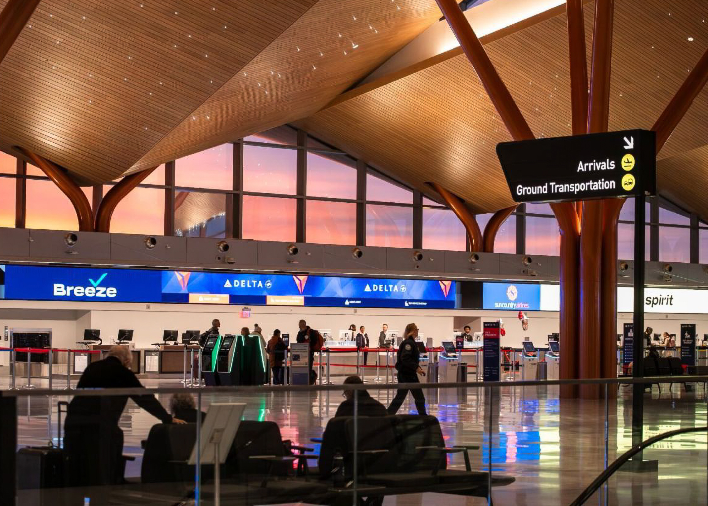 Interior of a modern airport terminal ticketing area during sunset.