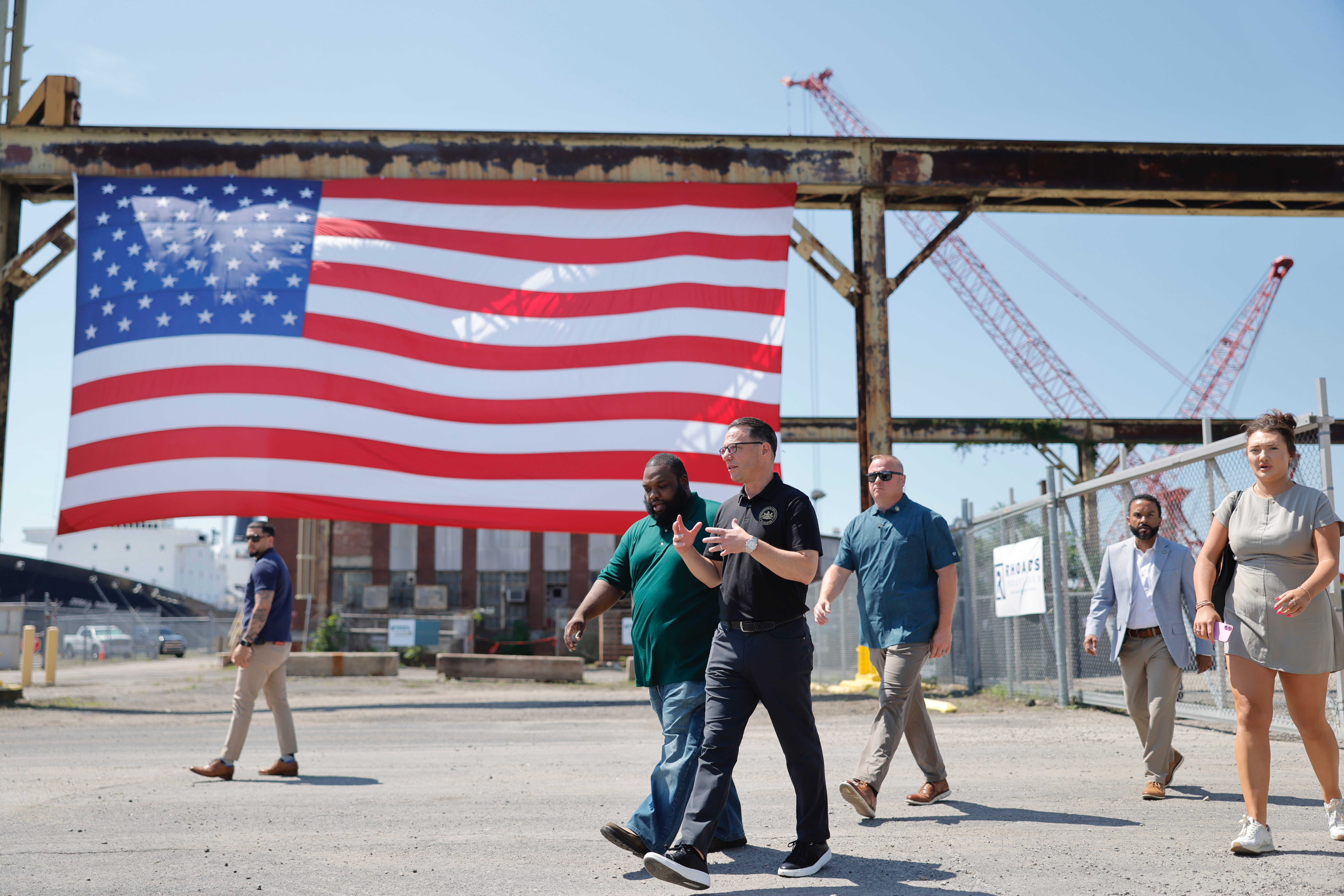 CEO of Rhoads Industries and Gov. Josh Shapiro walk through a construction site, with a large American flag in the background.