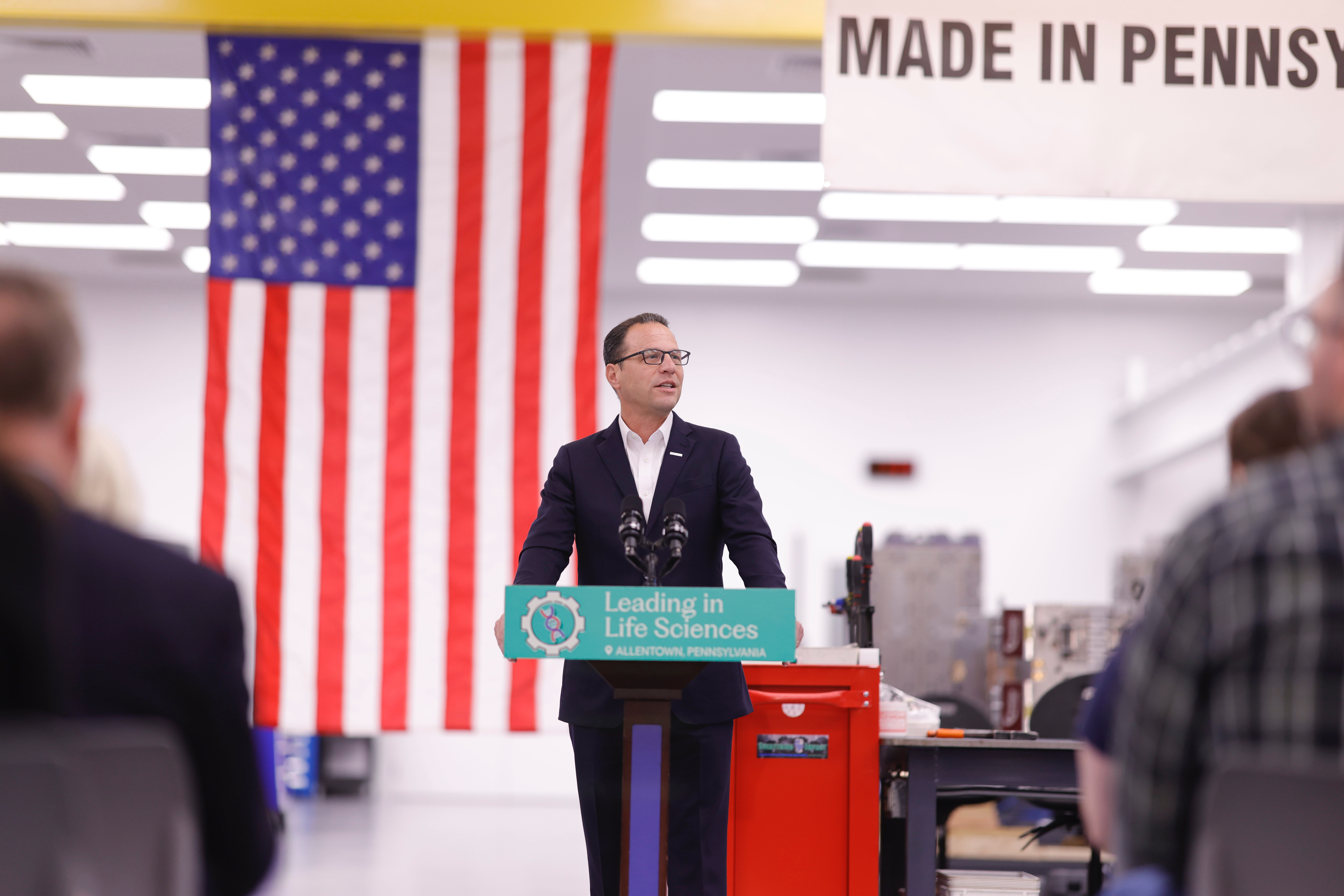 Governor Josh Shapiro speaks at a podium in front of an American Flag
