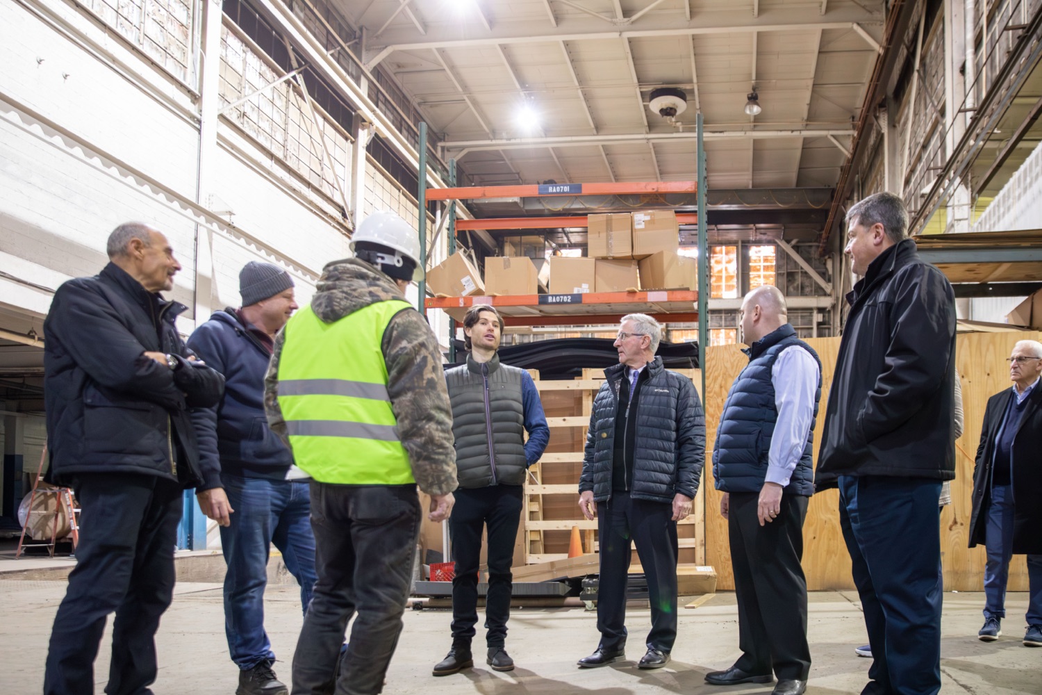 Leaders from the Shapiro Administration and Farm Plast executives huddle and talk in the company's manufacturing warehouse space.
