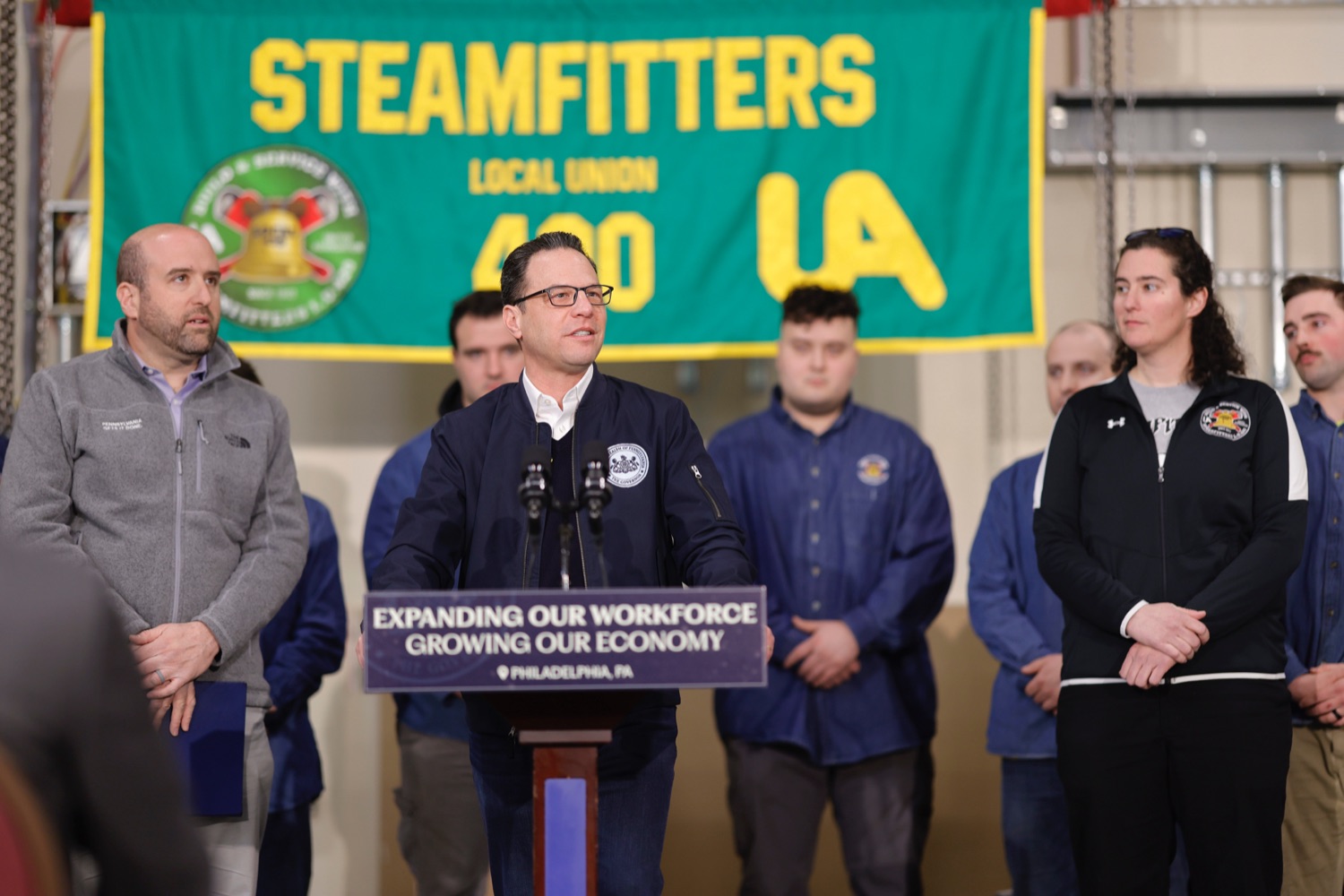 Gov. Josh Shapiro speaks a podium. A small group of people stands behind him.