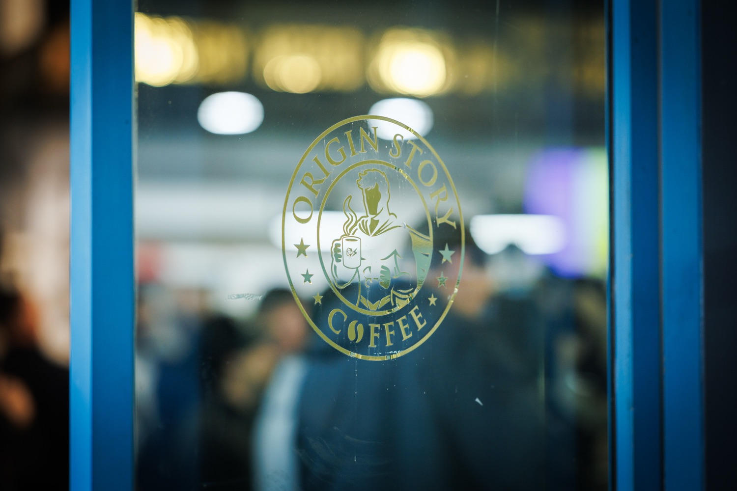 A logo for the company Origin Story Coffee, on a glass door.