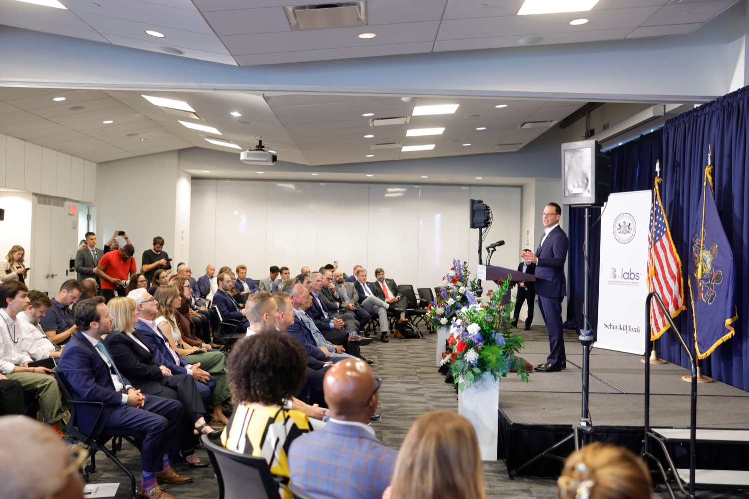 Governor Josh Shapiro speaks in front of a large crowd of businesspeople in a conference room