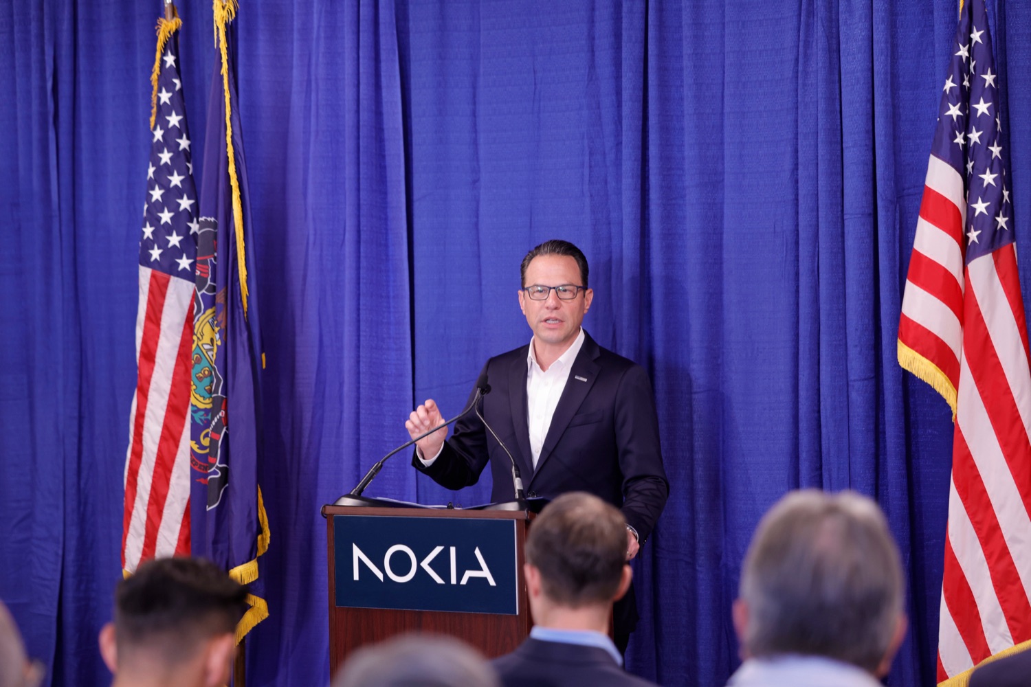 Governor Josh Shapiro speaks at a Nokia-branded podium in front of a blue backdrop.