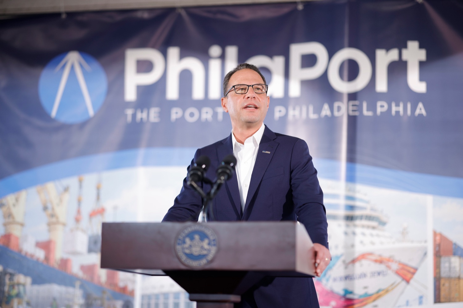 Governor Josh Shapiro speaks at a podium. A large banner with Philaport branding is visible behind him.