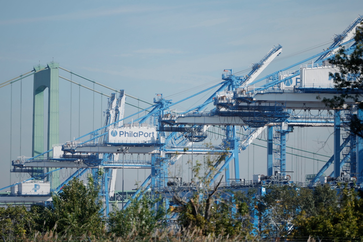 Cargo cranes near a large bridge, against a dark sky
