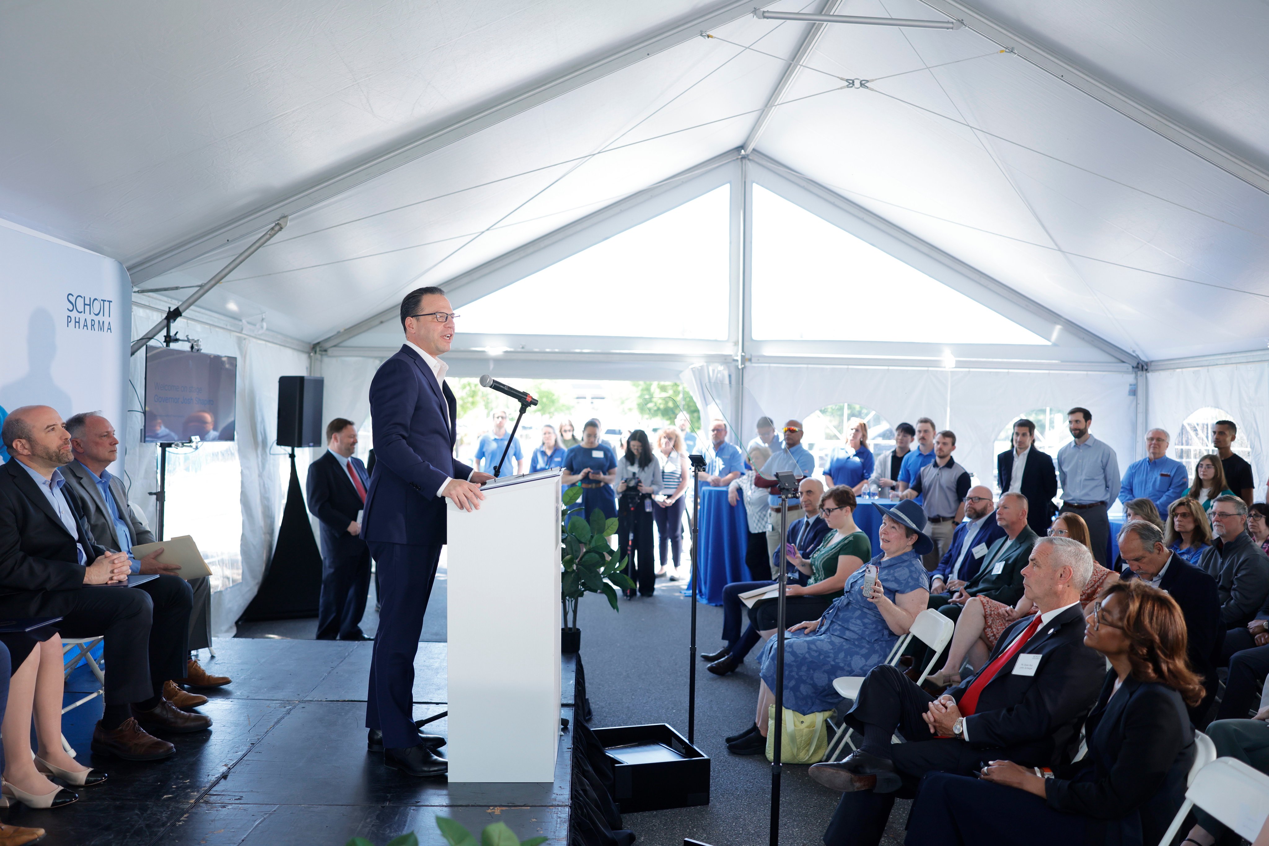 Governor Josh Shapiro speaks at a podium to a group of businesspeople and government officials during an event 