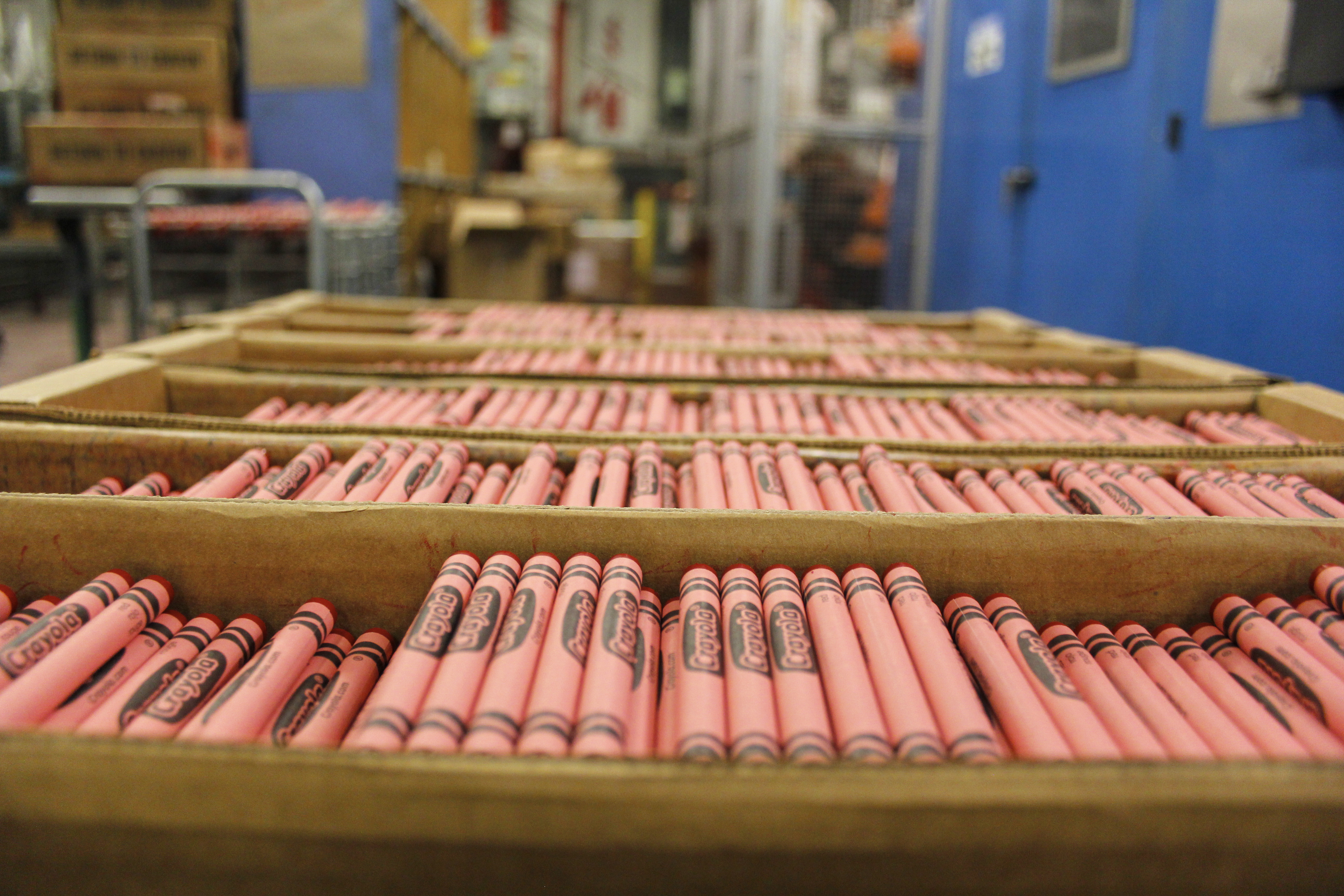 Red Crayola crayons sit in large boxes in a Crayola factory