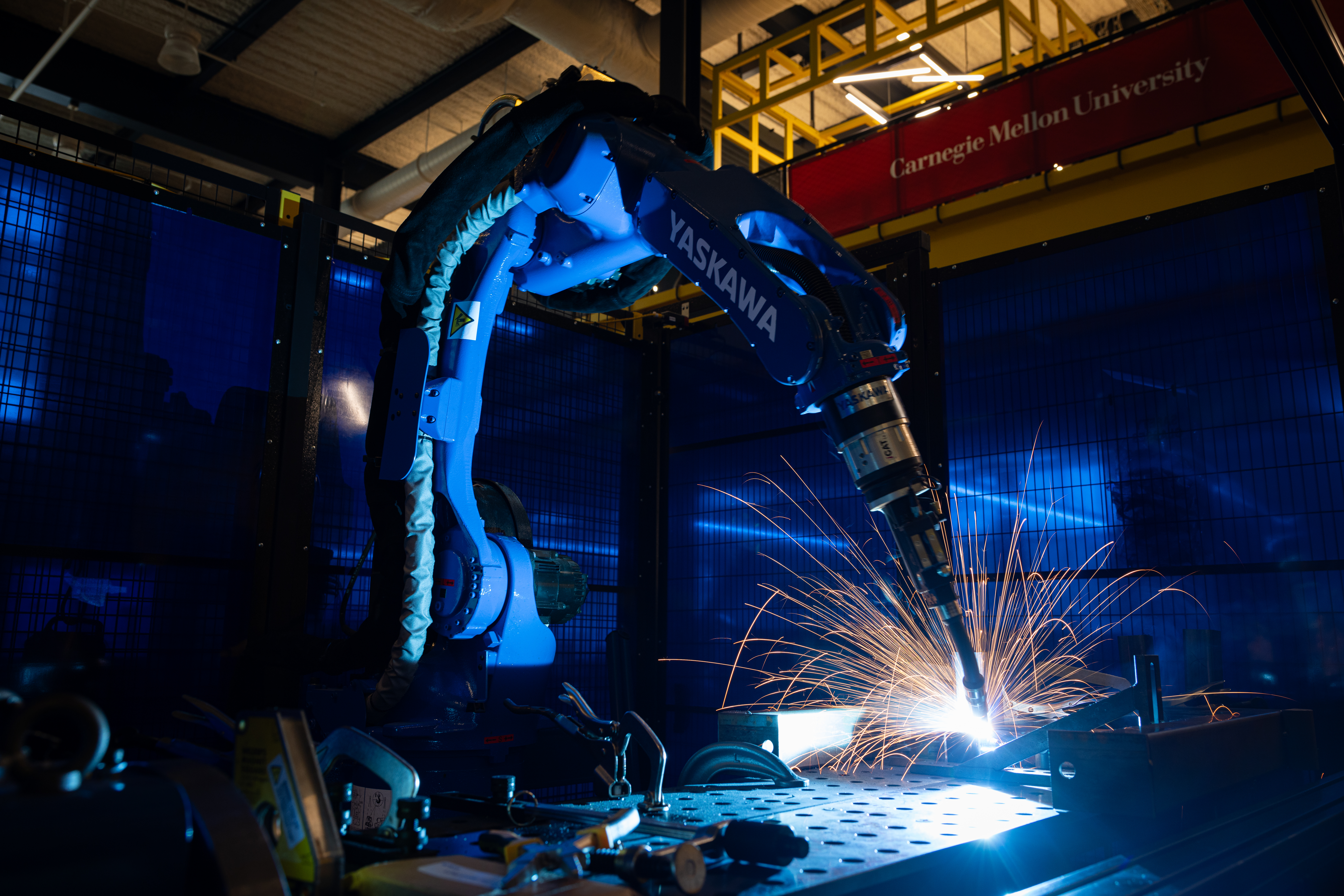 Sparks fly from a robotic arm welding sheet metal in a dark room